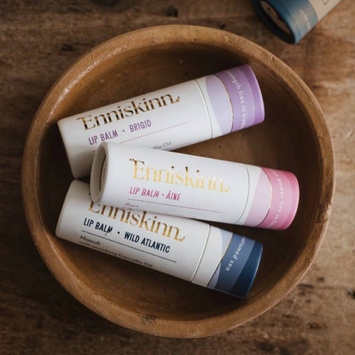 Connemara Country Enniskinn natural lip balms in paper tubes arranged in a rustic wooden bowl