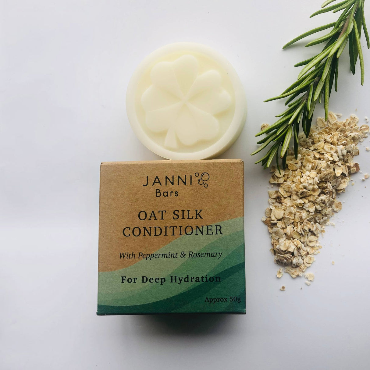 Connemara Country Janni Bars oat silk conditioner bar with peppermint and rosemary next to fresh herbs and oats.
