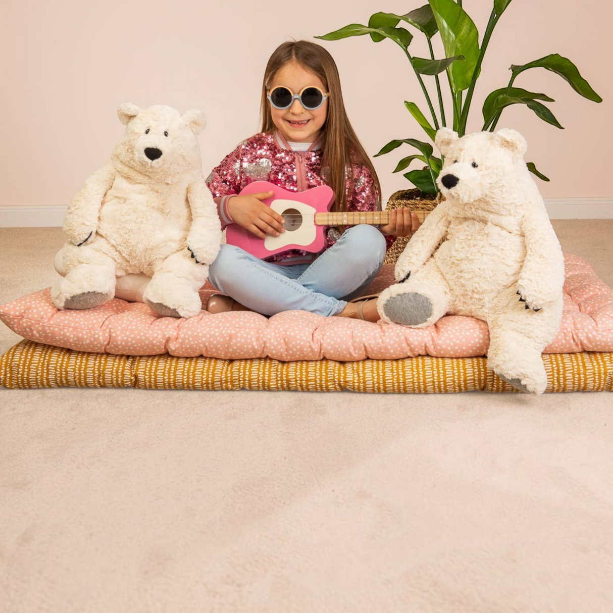 Connemara Country girl playing a toy guitar with two fluffy Teddy Hermann Polar Bear Jones plush toys on cushions.