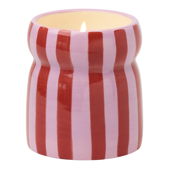 Connemara Country Paddywax Cabana ceramic candle with red and pink vertical stripes and a lit wick