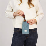 Connemara Country blue corduroy glasses case with zipper and beige cord handle held by a woman in a white sweater.