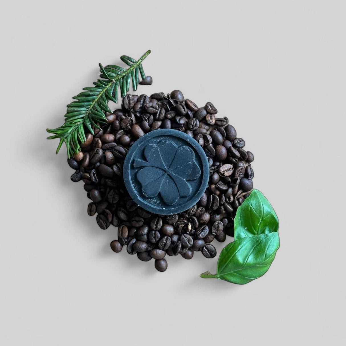 Connemara Country Janni Bars charcoal conditioner bar with clover design on coffee beans with pine and basil leaves.