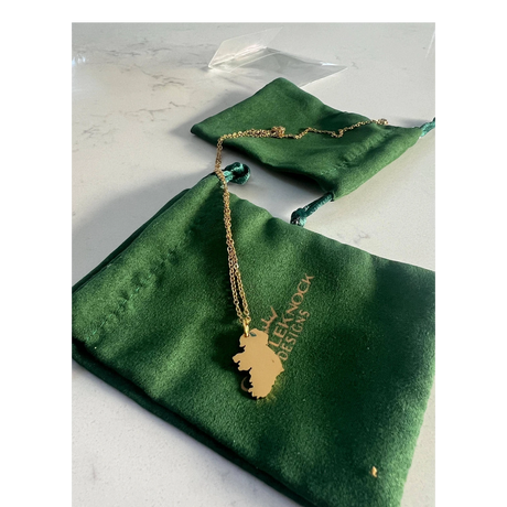 CastleKnock Designs gold Map of Ireland pendant necklace on a delicate chain, presented in a green pouch.