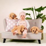 Connemara Country toddler sitting on a small sofa with three beige Teddy Hermann soft plush dogs