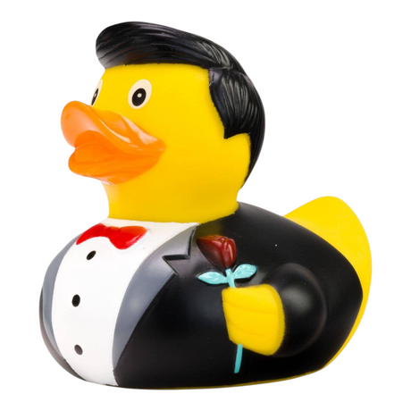 Connemara Country rubber duck groom wearing a black tuxedo, white shirt, red bow tie, and holding a red rose.